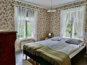 a bedroom with a bed and two windows at Sundholms Gård - Sundholmin Tila in Kokkola