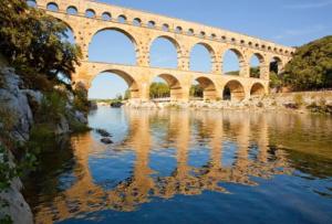 a bridge over a river with reflections in the water at Gite les Coquelicots in Lédenon