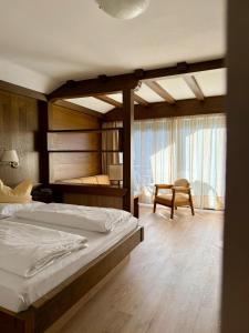 a bedroom with a large bed and a chair at Hotel Am Wolfgrubenersee in Soprabolzano +53 photos