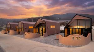 a group of buildings with a sunset in the background at Ganghwa Aiem Glamping in Incheon