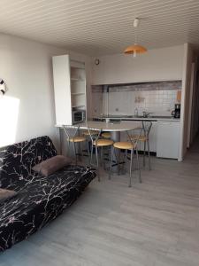 a living room with a couch and a table and chairs at Cocon Marin 2 Etoiles - Face Océan et Balcon in Fort-Mahon-Plage