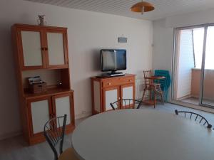 a room with a table and a tv and chairs at Cocon Marin 2 Etoiles - Face Océan et Balcon in Fort-Mahon-Plage