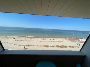 a view of a beach from a window at Cocon Marin 2 Etoiles - Face Océan et Balcon in Fort-Mahon-Plage