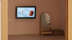 a television on a wall with a picture of an apple at Boryeong (Daecheon) Jeil Pension in Boryeong