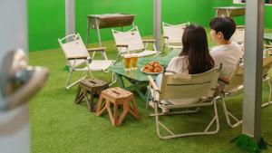 two people sitting at a table with a bowl of fruit at Boryeong (Daecheon) Jeil Pension in Boryeong +1 photo