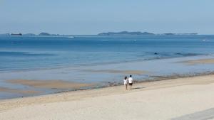 two people walking on a beach near the water at Boryeong (Daecheon) Jeil Pension in Boryeong