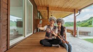 two women sitting on a porch holding a cell phone at Gapyeong Nature Pension in Gapyeong