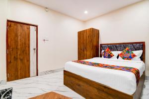 a bedroom with a large bed with a wooden headboard at FabHotel Adhiraj Inn in Kolkata
