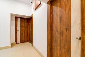 a hallway with a wooden door and white walls at FabHotel Adhiraj Inn in Kolkata