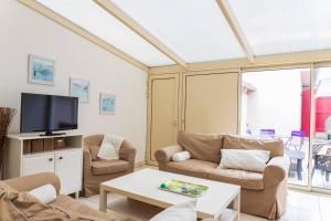a living room with couches and a tv and a table at Maison familiale quartier Quentovic in Le Touquet-Paris-Plage