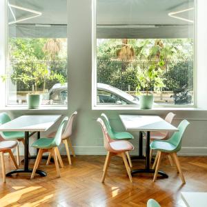 a row of tables and chairs in a restaurant with windows at Hotel Aria in Nice