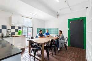 a group of people sitting around a table in a kitchen at Secret Garden Backpackers, Sydney in Sydney