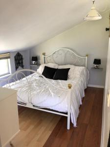 a bedroom with a white bed with black pillows at Gîtes Matignon 6 personnes in Matignon