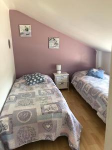 a bedroom with two beds and a purple wall at Gîtes Matignon 6 personnes in Matignon