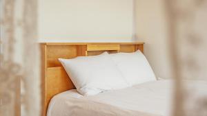 a bed with a wooden headboard and a white pillow at Gapyeong Ribbon Spa Pool Villa in Gapyeong