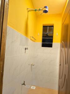 a bathroom with a shower with a yellow wall at Tulivu 2 stays in Nyahururu