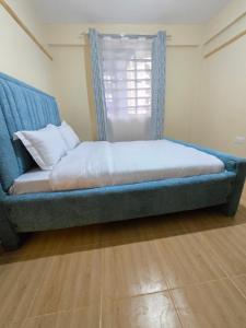 a bed in a room with a blue couch and a window at Tulivu 2 stays in Nyahururu