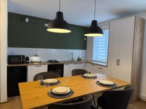 a kitchen with a wooden table with chairs and lights at TwinNest Petrila in Petrila +7 photos