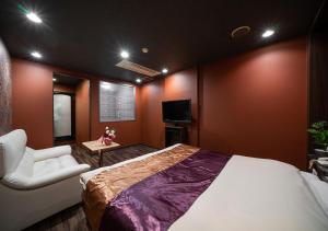a bedroom with a bed and a chair and a television at ホテルリンクス柏市豊四季店 in Kashiwa
