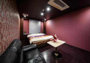 a bedroom with a bed and a couch and a table at ホテルリンクス柏市豊四季店 in Kashiwa