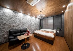 a bedroom with a bed and a black leather chair at ホテルリンクス柏市豊四季店 in Kashiwa