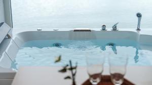 two wine glasses sitting in a bath tub at Yeosu Jangsuri Poolvilla&Spa Pension in Yeosu