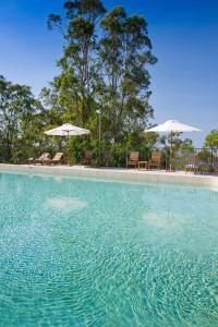 a large pool of water with chairs and umbrellas at Mercure Clear Mountain Lodge in Mount Samson