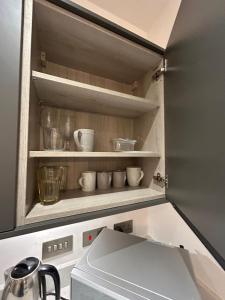 a kitchen with cups and bowls on a shelf at The Courthouse Stylish Serviced Living in Ramsgate
