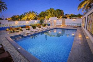 a swimming pool with lounge chairs in a backyard at Astralis Hotel - Hot Air Balloon View in Al Aqālitah