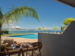 a patio with a table and chairs and a pool at Ionian Hill Hotel in Argassi