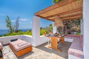 a patio with a wooden table and a bench at Villa Cleio where the sea meets absolute calm in Skiathos