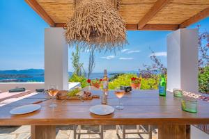 a wooden table with wine glasses and a view of the ocean at Villa Cleio where the sea meets absolute calm in Skiathos +23 photos
