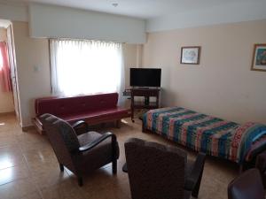 a room with a bed and a couch and a tv at ELINOR-CASA PLAYERA - a 2 cuadras de la playa in Santa Clara del Mar