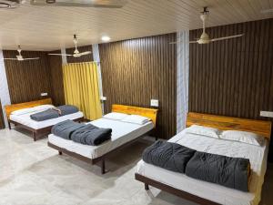 a room with three beds in a room at Adventure Inn Dandeli in Kurandi