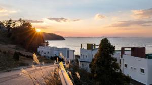 a sunset over the ocean with white buildings at Yeosu Arungeorida Ocean View Pension in Yeosu
