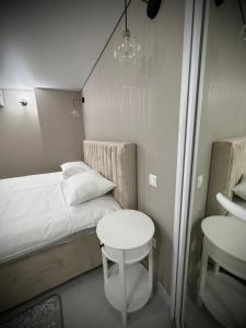 a small bedroom with a white bed and a table at Casa in centrul Chisinaului in Chişinău