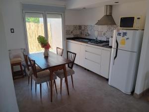 a kitchen with a table and a white refrigerator at ELINOR-CASA PLAYERA - a 2 cuadras de la playa in Santa Clara del Mar
