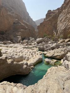 a pool of water in a canyon with rocks at Wadi hawer tour guiding and local farm tour in Biḑ‘ah