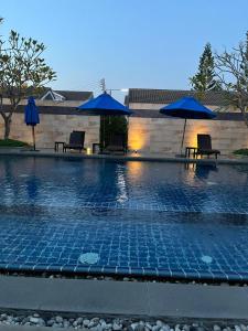 a swimming pool with two chairs and umbrellas at Wilfrid villa in Hua Hin