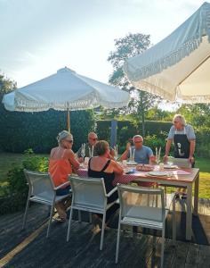 a group of people sitting at a table under an umbrella at TheGilgahouse Fjordroom in Nakskov