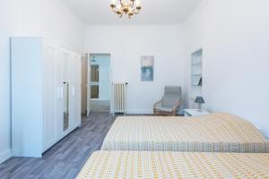 a white bedroom with a bed and a chair at Happyfew maison Michelet in Nice
