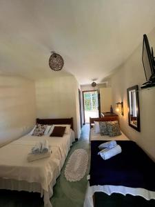 a room with two beds and a window at Pousada Marauá - Na beira do mar de Cumuru in Cumuruxatiba