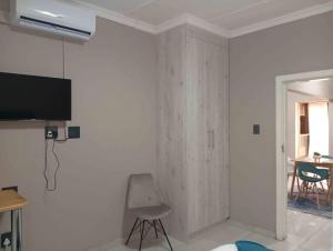 a white room with a chair and a tv on a wall at Joyful Home Bela-Bela in Bela-Bela