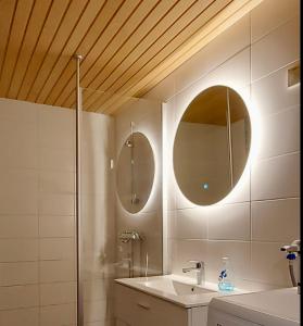 a bathroom with a sink and two mirrors on the wall at Herranterttu Apartments in Saariselka +80 photos