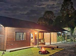 a log cabin with a fire in the yard at night at Casa Completa | 2 Suítes + Jardim com Fogo de Chão in Urubici