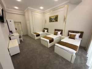 a room with three beds and a table and chairs at The Avenue Hotel in Kogon