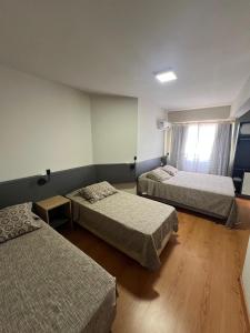 a room with three beds and a window at Hoteis Cattoni Executive in Lages