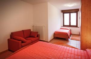 a living room with a red couch and a bed at Albergo Diffuso Tolmezzo in Tolmezzo