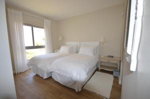 a white bedroom with a large bed and a window at Chardon in Langebaan