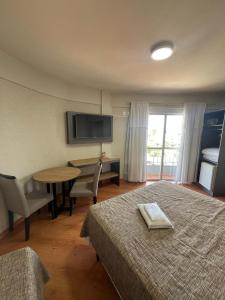 a hotel room with two beds and a table and a television at Hoteis Cattoni Executive in Lages